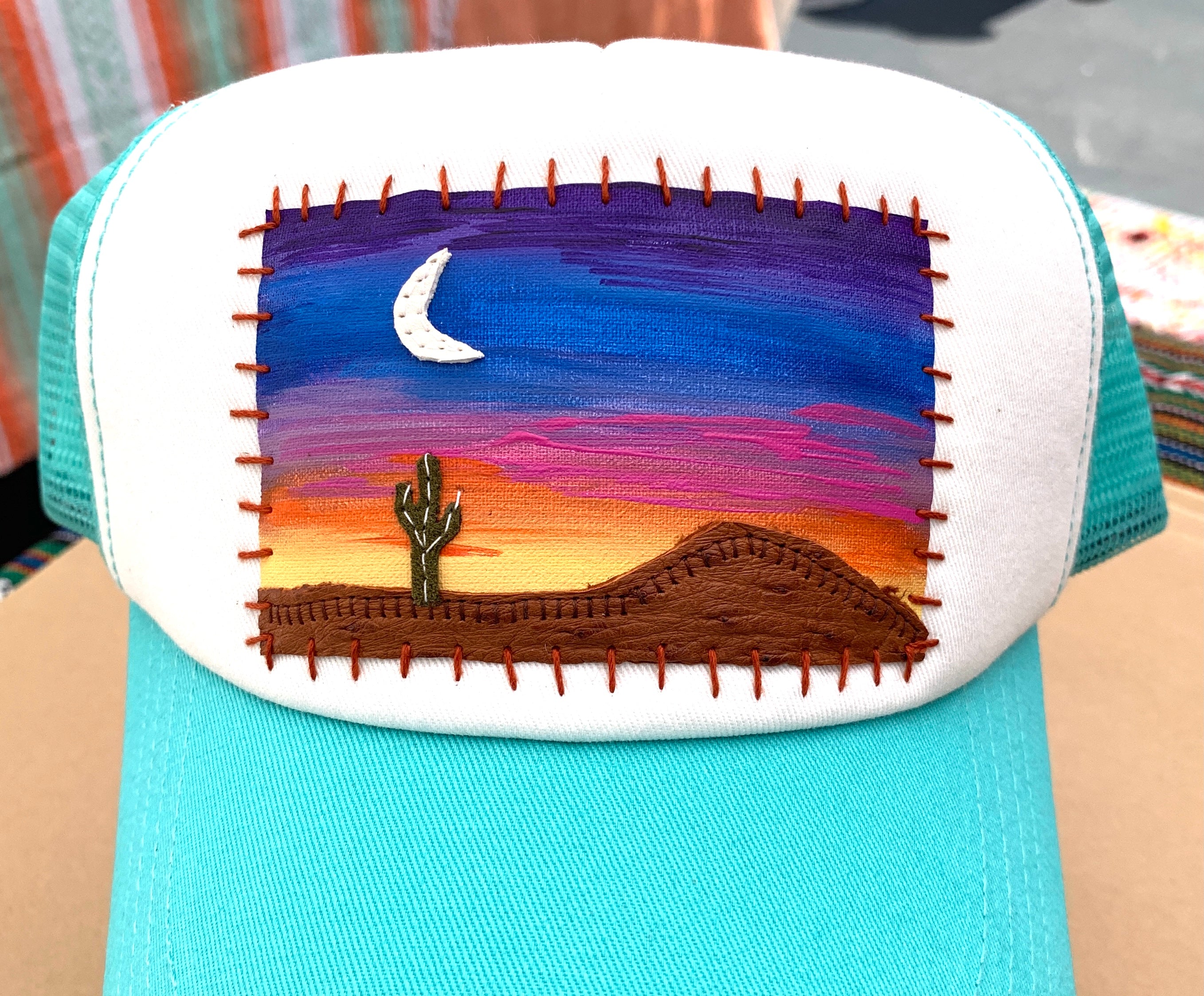 Hand painted patch featuring a sunset, cactus, moon, and mountain.